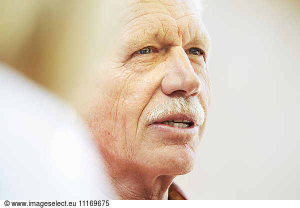Portrait of a senior man with moustache sitting outdoors.