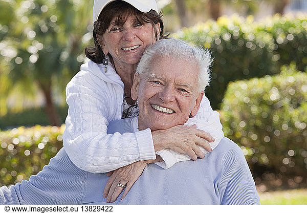 Portrait of a senior woman hugging a man from behind