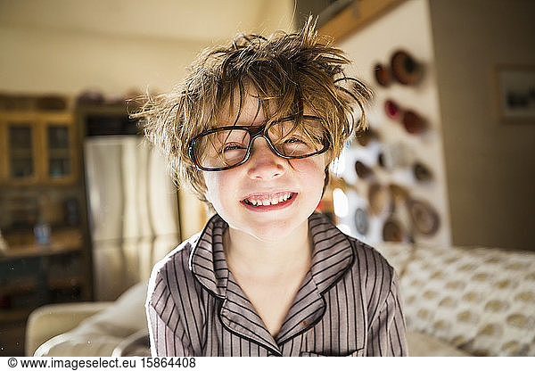 Portrait of a six year old boy with disheveled hair and oversized glasses waking up. Bedhead hair.