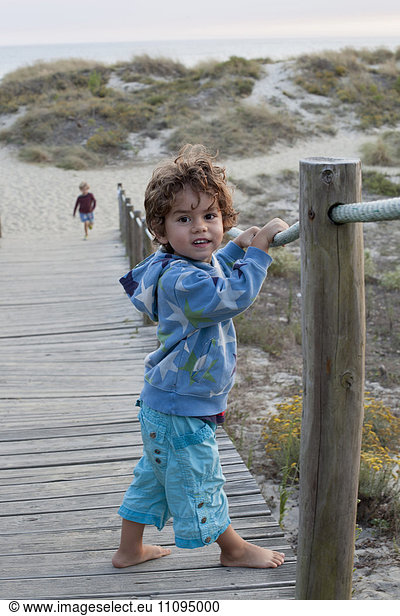 Portrait of a small child standing on boardwalk at the beach  Viana do Castelo  Norte Region  Portugal