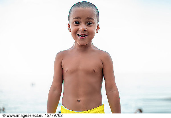 Portrait of a smiling boy wearing swimming trunks  looking at camera.