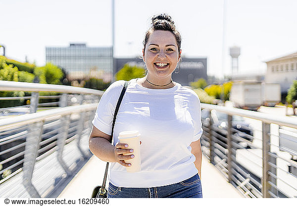 Portrait of a smiling curvy young woman with takeaway drink in the city