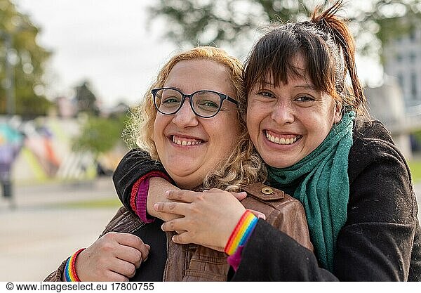 Portrait of a smiling lesbian couple hugging each other while standing together outdoors  looking at camera