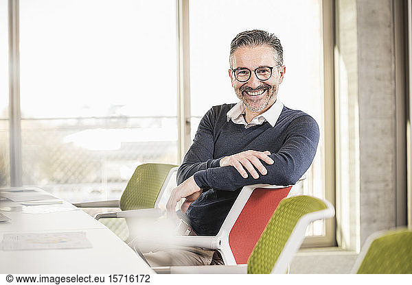 Portrait of a smiling mature businessman sitting at desk in office
