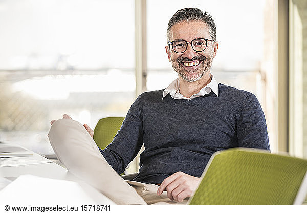 Portrait of a smiling mature businessman sitting at desk in office