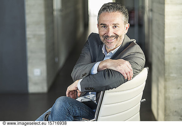 Portrait of a smiling mature businessman sitting on chair in office