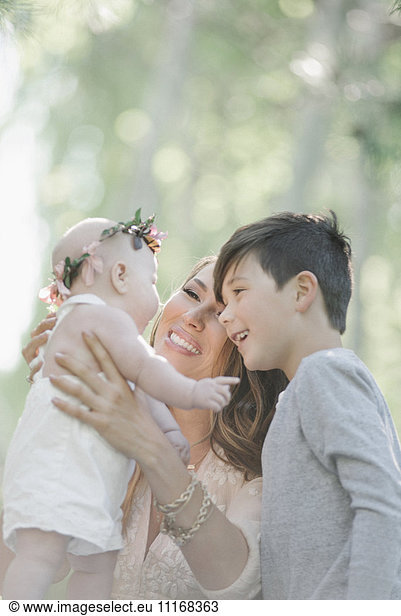 Portrait of a smiling mother  boy and baby girl with a flower wreath on her head.