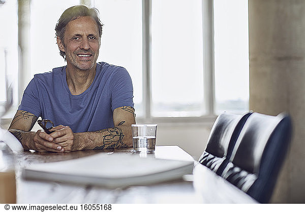 Portrait of a smiling senior man sitting at the table in a loft flat