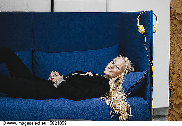 Portrait of a smiling young businesswoman lying on couch