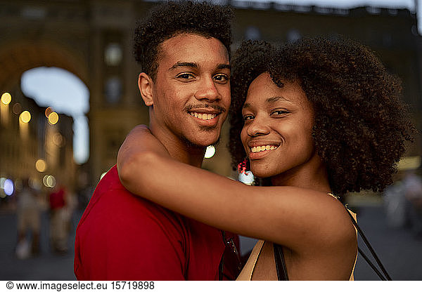 Portrait of a smiling young tourist couple in the city at dusk  Florence  Italy