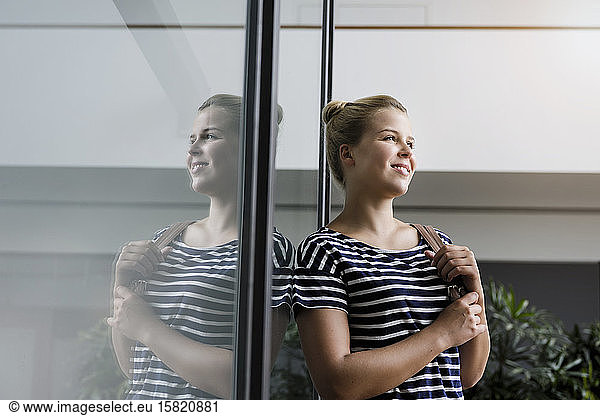 Portrait of a smiling young woman in office reflected in glass pane
