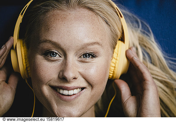 Portrait of a smiling young woman listening to music with headphones