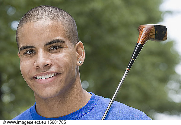Portrait of a teenage boy holding a golf club and smiling