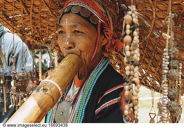 Portrait of a woman from a Thai tribe playing a musical instrument.