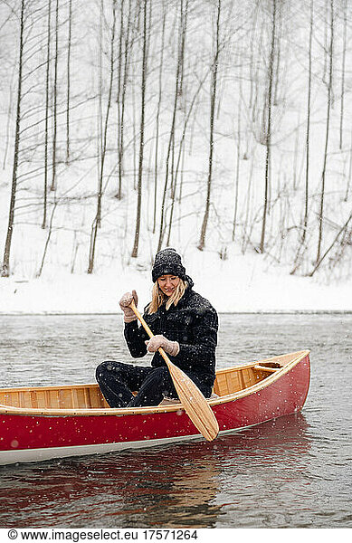 Portrait of a woman in a red canoe boat in winter.