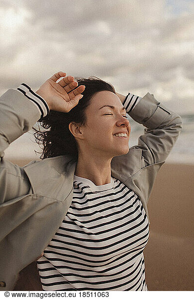 portrait of a woman in a trench coat walking on a sandy beach