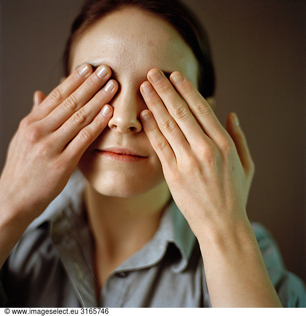 Portrait of a woman with her hands on her eyes.