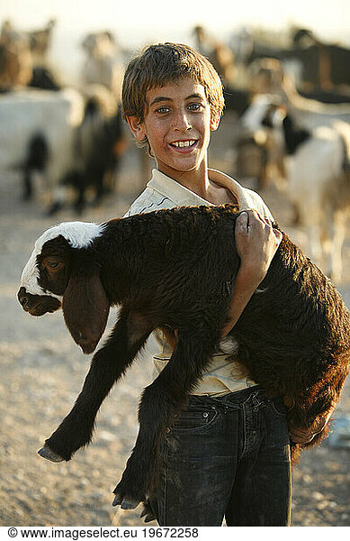 Portrait of a young boy holding a goat