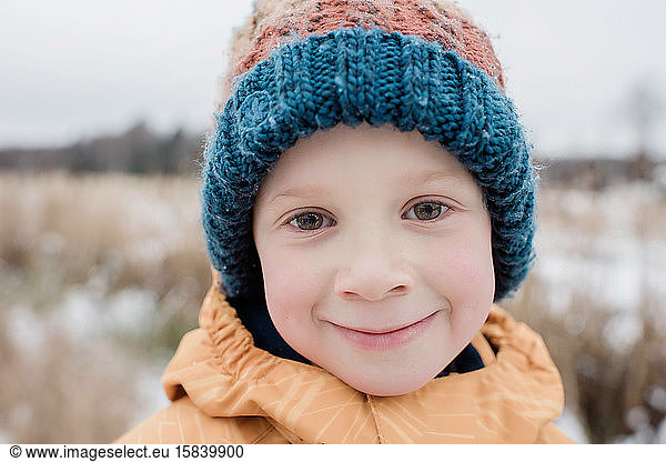 portrait of a young boy smiling whilst playing outside in winter