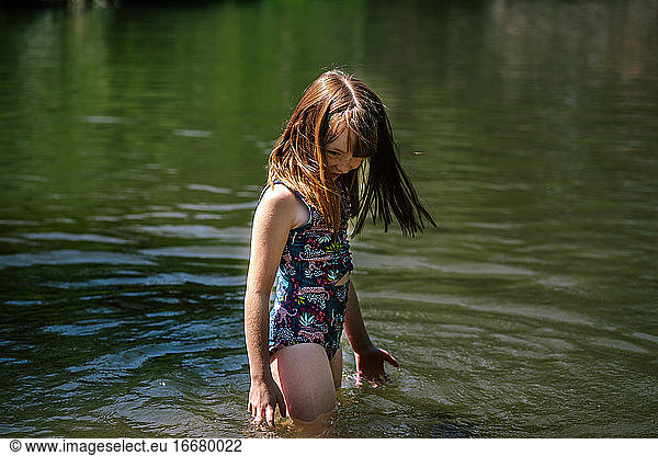 Portrait of a young happy girl playing in a river on a sunny day