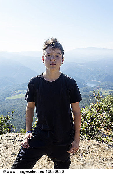Portrait of a young male with black t-shirt standing against mountains