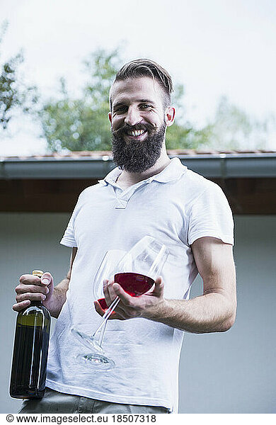 Portrait of a young man holding red wine with glasses  Bavaria  Germany