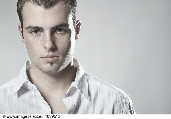 Portrait of a young man wearing a white shirt looking into camera