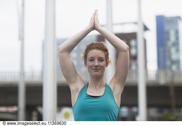 Portrait of a young woman doing lotus pose yoga in urban city