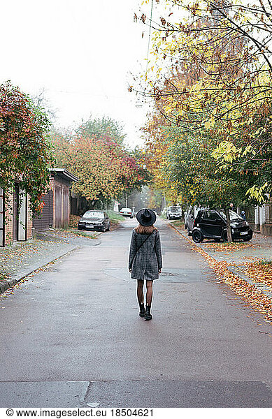 Portrait of a young woman in a gray coat on an autumn city street