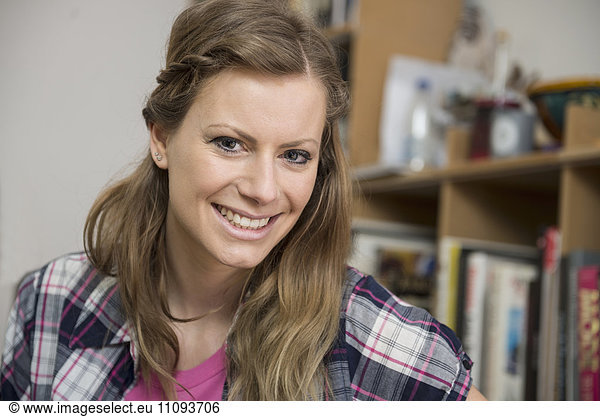 Portrait of a young woman in living room and smiling  Munich  Bavaria  Germany