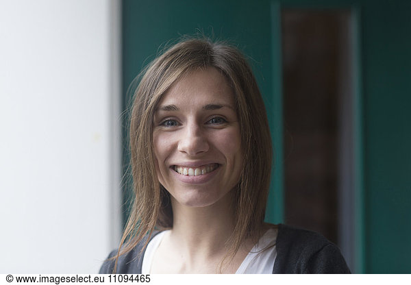 Portrait of a young woman smiling in front of house door