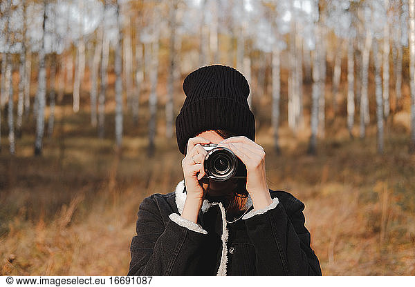 Portrait of a young woman with camera taking a picture in beauti