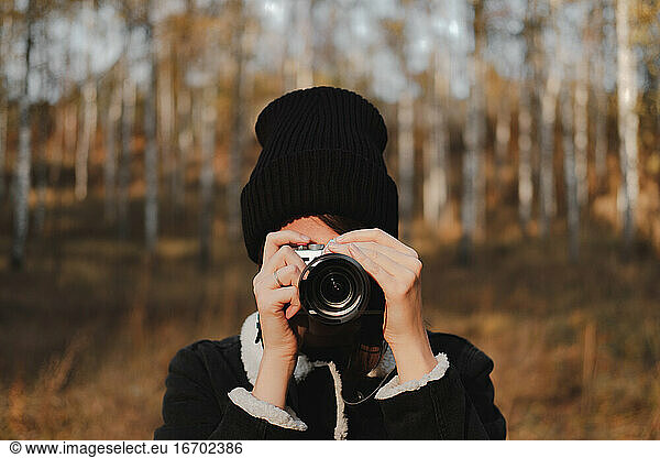 Portrait of a young woman with camera taking a picture in beauti