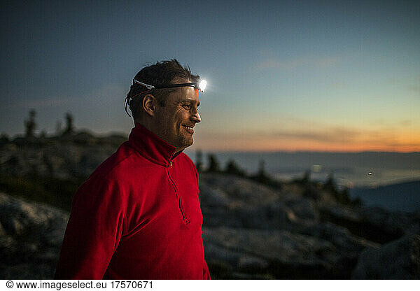 Portrait of active smiling man wearing headlamp while trail running.