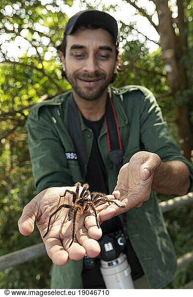 Portrait of adult man holding big tarantula spider on hand