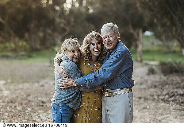 Portrait of Adult Woman and Senior Parents Hugging at Park