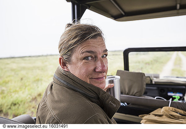Portrait of adult woman in the front seat of a safari vehicle looking over her shoulder.