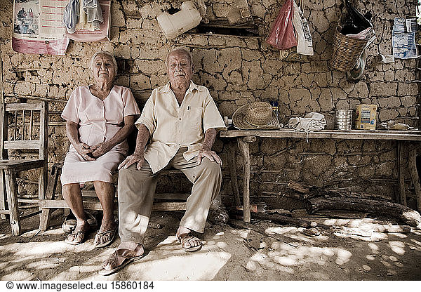 Portrait of an adorable couple of grandparents in their humble house in the countryside. Adobe house.