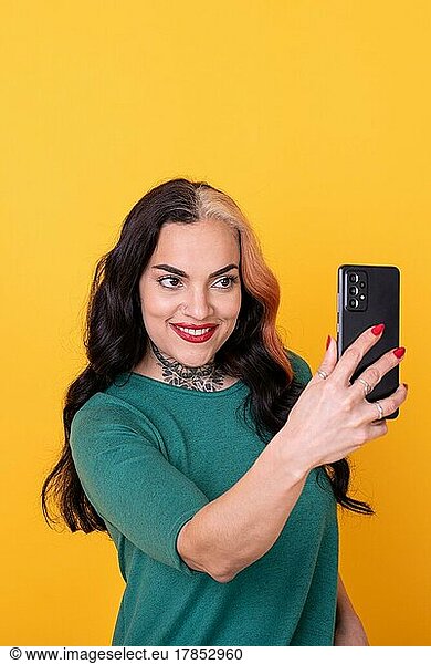 Portrait of an attractive woman using smart phone over yellow background. Copy space