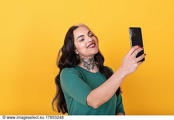 Portrait of an attractive woman using smart phone over yellow background. Copy space
