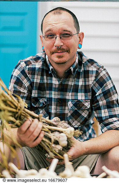 portrait of an urban farmer while processing his cured hardneck garlic
