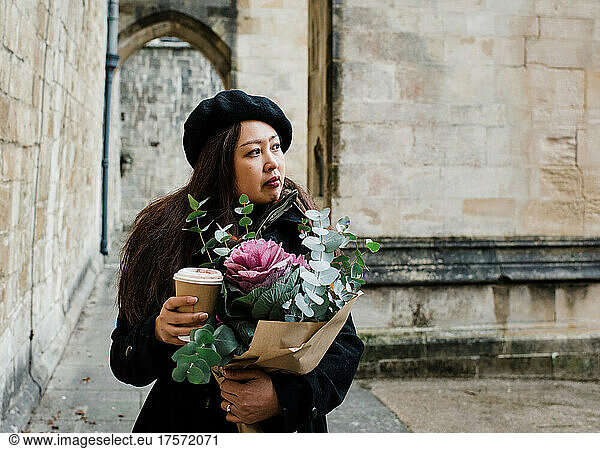 Portrait of Asian woman holding a bouquet of flowers and coffee