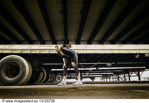 Portrait of athlete standing amidst vehicle trailers