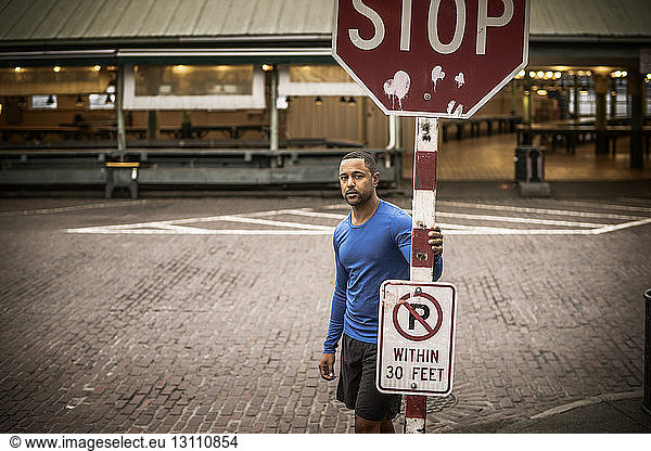 Portrait of athlete standing by stop sign on street