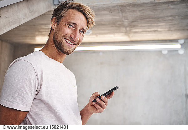 Portrait of attactive young man wearing white t-shirt holding smartphone