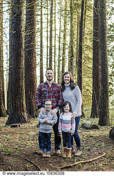 portrait of attractive family standing in the forest.