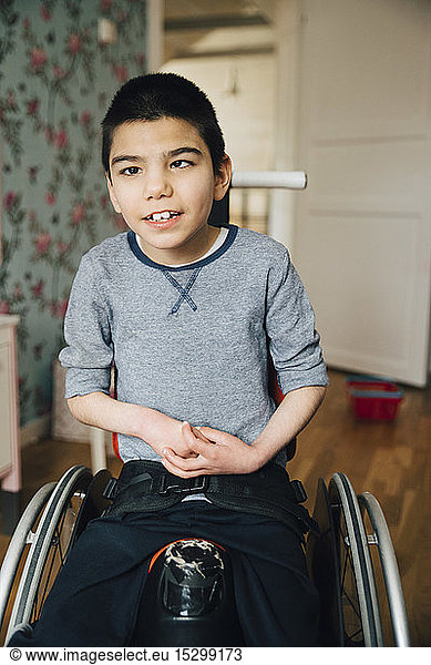 Portrait of autistic boy sitting on wheelchair at home