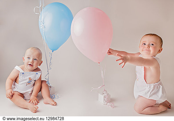 Portrait of baby boy and baby girl with balloons and birthday presents