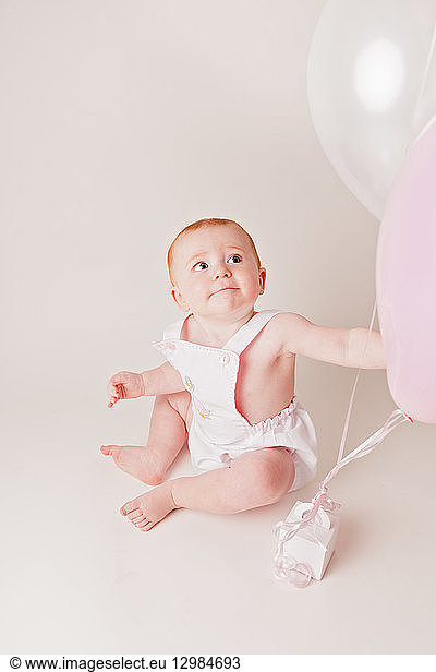 Portrait of baby girl with balloons and birthday present