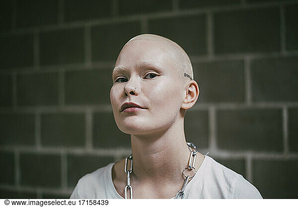 Portrait of bald female activist against wall
